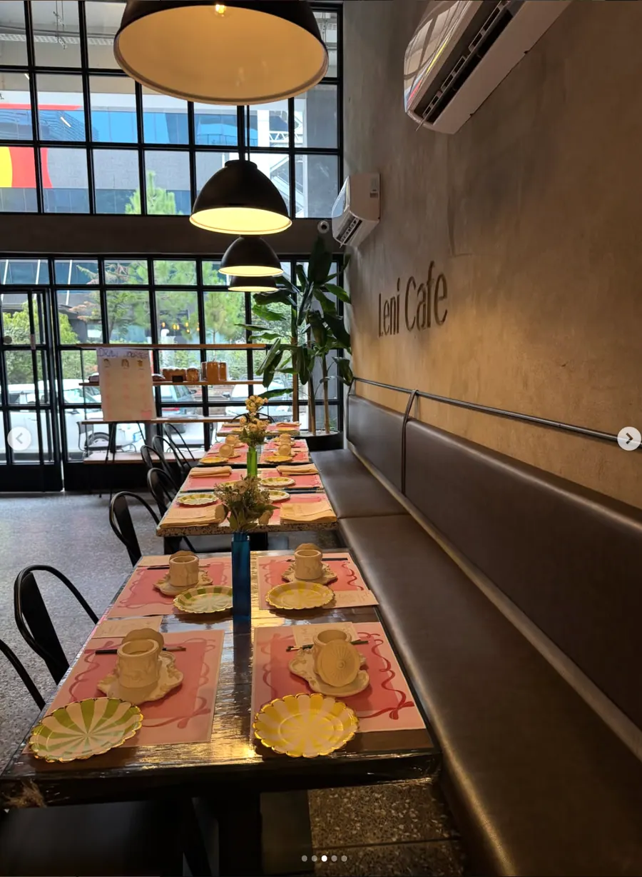 Warm café lighting above long tables prepared for an Art Nook workshop at Leni Café