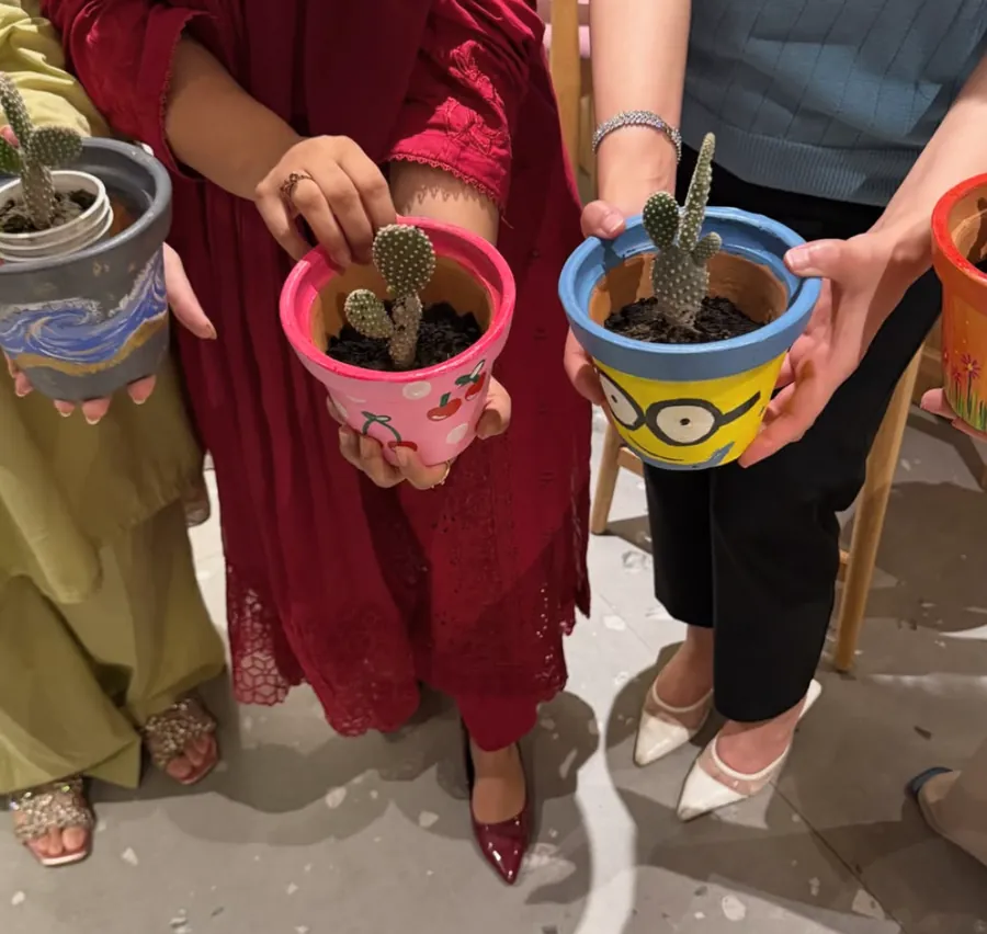 Workshop guests holding their finished hand-painted cactus pots